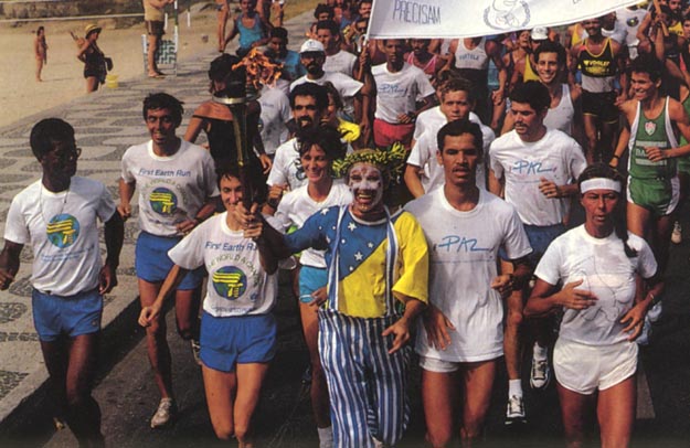 A clown dressed in the colors of the Brazilian flag having fun running with the torch. Rio de Janeiro, Brazil