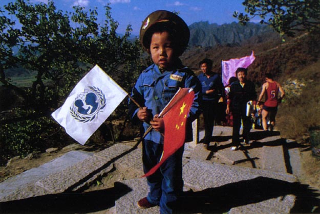 Young boy with UNICEF and Chinese Flags at Great Wall of China ceremony.