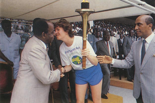 President Felix Houphouet celebrates his 81st birthday with torch and kiss by Canadian global runner Patty Anglin. Abidjan, Cote d’ Ivoire