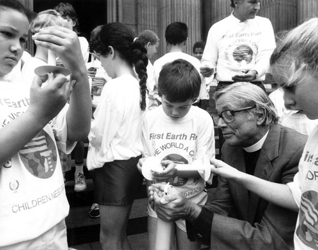 Dean of St Paul’s Cathedral, Alan Webster, lighting peace candles with children of many ethnic backgrounds. London, England