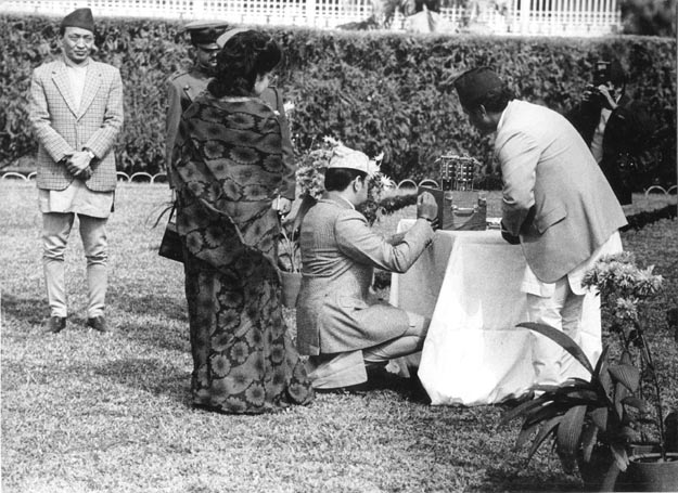 King Birendra of Nepal signs miner’s lamps housing the flame on the grounds of Katmandu Royal Palace. Katmandu, Nepal